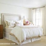 White bedroom with a bed, lamps, and decorative sculpture.