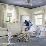Blue and white bedroom with twin beds, curtains, and furniture.