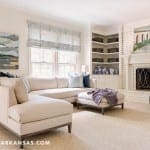 Cream-colored sectional sofa with two ottomans in a living room.