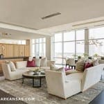 Modern living room with a white sofa, gray rug, and city view.