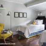 Gray bedroom with a queen bed, yellow armchair, and wooden floors.