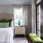 Master bedroom with patterned curtains, bed, nightstand, and bench.