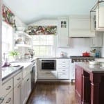 White kitchen with red island, patterned window treatments, and wood flooring.