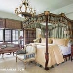 Four-poster bed with draped canopy and ornate chandelier.