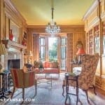 Wood-paneled library with built-in bookshelves and a chandelier.