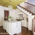 White kitchen with patterned ceiling, wooden staircase, and island.