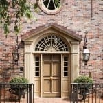 Brick facade with arched doorway and window, flanked by lanterns.