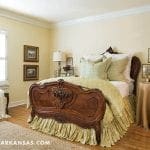 Four-poster bed with ornate headboard and green bedding.