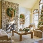 Stone fireplace with wreath, large windows, and Christmas tree.