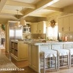 Cream-colored kitchen with stone fireplace and island bar stools.