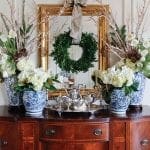 Dark wood cabinet with floral arrangements and a wreath.