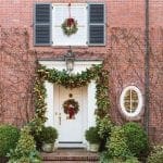 Red brick house with wreaths and garland, window, and porch.