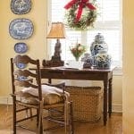 Wooden desk with woven basket, blue and white porcelain plates, and a wreath.