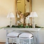 Console table with mirror, angel statue, and lamps.
