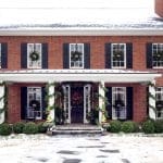 Brick house with black shutters, decorated for winter.