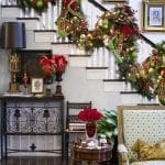 Decorated staircase with garland, portraits, and holiday accents.