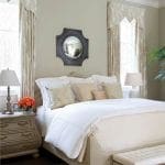 Cream-colored bed with patterned drapes and a mirror.