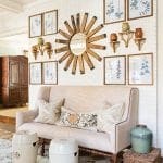 Brick wall with framed botanical prints and a wooden sunburst decoration.