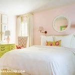 Pink bedroom with green furniture, framed artwork, and a window.