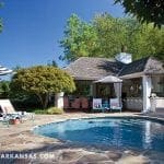 Poolside cabana with bar and dining area, lounge chairs, and umbrellas.