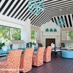 Covered patio with black and white striped ceiling, teal tables, and orange patterned chairs.