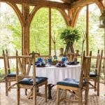 Screened porch dining area with rustic wooden chairs and table set for six.