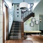 Hallway with dark wood staircase, patterned runner, yellow bench, and cowhide rug.