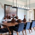 Dining room with light blue walls, wooden table, navy chairs, and brown vases.