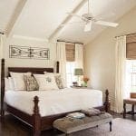 Bedroom with white vaulted ceiling, dark wood bed, and quilted white bedding.