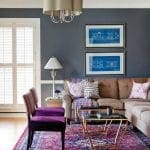 Living room with dark blue walls, brown sectional sofa, purple chairs, and ornate rug.