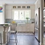 Kitchen with white cabinets, farmhouse sink, stainless steel appliances, and dark tile floor.