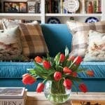 Turquoise sofa with plaid and floral pillows, coffee table with tulips and books