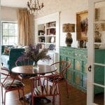 Dining area with round table, red chairs with zebra print cushions, and teal cabinet.