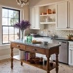 Kitchen with white cabinets, marble island, and patterned tile backsplash.