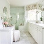 White bathroom with marble floor, vanity, and glass shower stall.