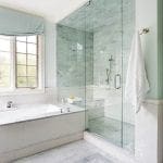 Bathroom with marble shower, white subway tile, and marble floor.