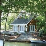 Wooden house with stone steps leading to a lake with a boat docked