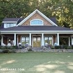Craftsman style house with brown siding, white columns, and stone landscaping.