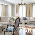 Living room with neutral sofas, patterned armchair, and ornate chandelier.