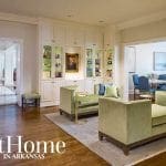 Living room with green velvet sofas, built-in white cabinets, and a portrait