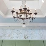 Chandelier above green banquette seating and chinoiserie wallpaper