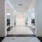 Hallway with marble and black tile floor, white columns, and double doors at the end.