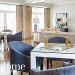 Living room with blue upholstered chairs around white tables, one with a board game.
