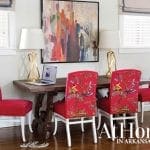 Desk with laptop and two gold lamps, surrounded by red chairs with ornate patterns.