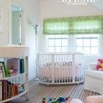 Nursery with white crib, striped rug, and changing table with books.