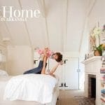 Bedroom with vaulted ceiling, white walls, bed, fireplace, and tall bookshelf.