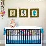 Nursery with white crib, floral bedding, and wall art with moss-covered frames