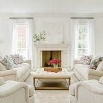 Living room with fireplace, two sofas, two armchairs, and tufted ottoman.