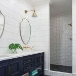 Navy blue double vanity with brass hardware, white shiplap walls, and subway tile shower.