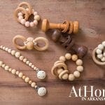Wooden baby toys including pacifier clips, rattles, and teethers on a wooden surface.